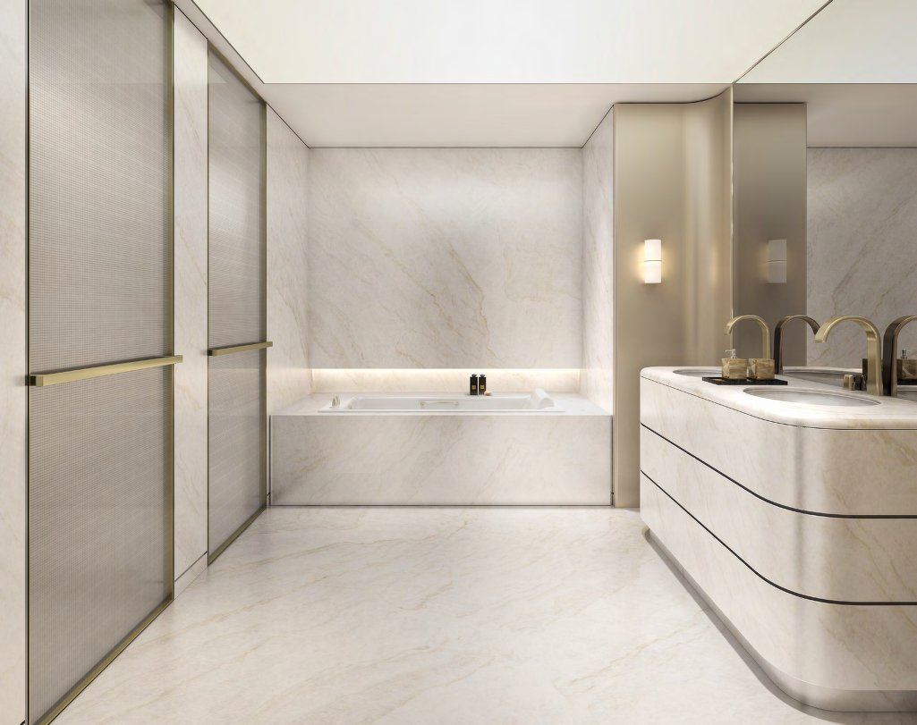 Pale marble bathroom with curved double vanity, bath and brass fittings