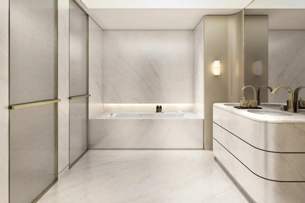 Pale marble bathroom with curved double vanity, bath and brass fittings