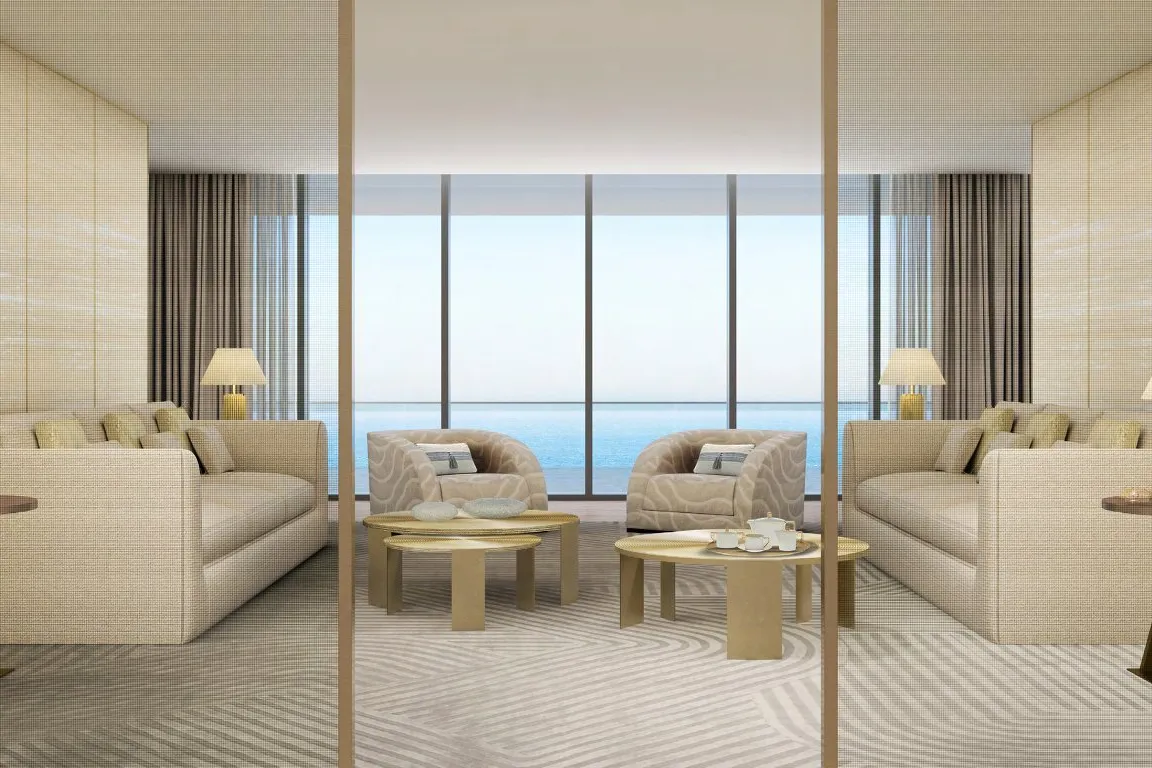 Sand-toned sitting room with sofas, brass tables and a wide sea view
